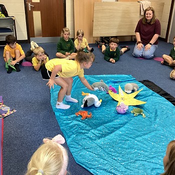 plentyn gyda pyped siarc yn sefyll ar y blanced glas.