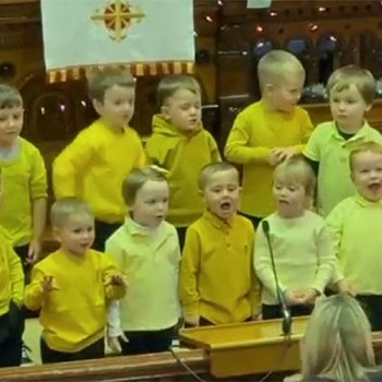 Young children wearing yellow singing in there christmas concert