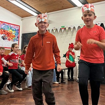 Dau plentyn yn gwisgo coch yn dawnsio yn y gwasanaeth