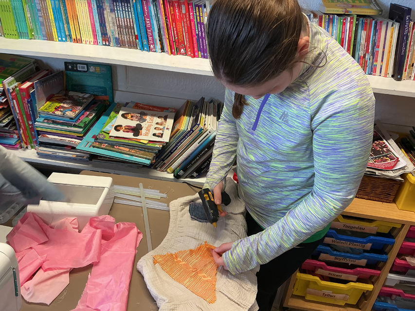 student using a glue gun to stick fabric down