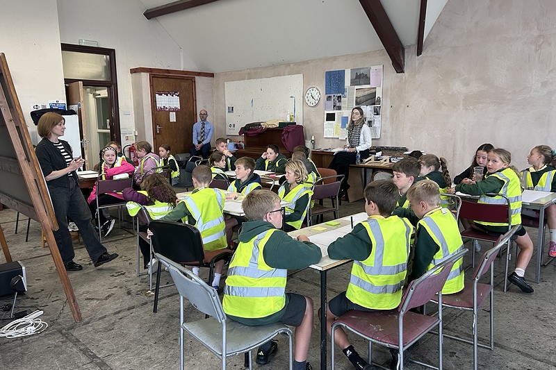 dosbarth o fyfyrwyr yn eistedd i lawr mewn gwelededd uchel