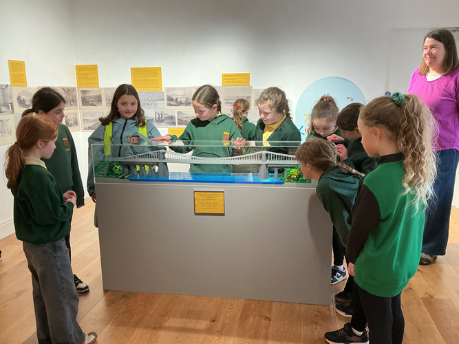 students looking at a bridge made from lego
