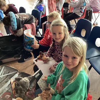 3 myfyriwr yn eistedd ar gadair yn dal llyfrau