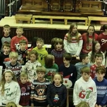 students in christmas jumpers singing