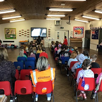 myfyrwyr yn y neuadd yn eistedd ar seddi coch