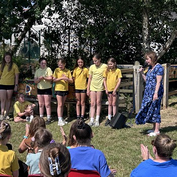 dynes yn dal meicroffon ac yn siarad â myfyrwyr
