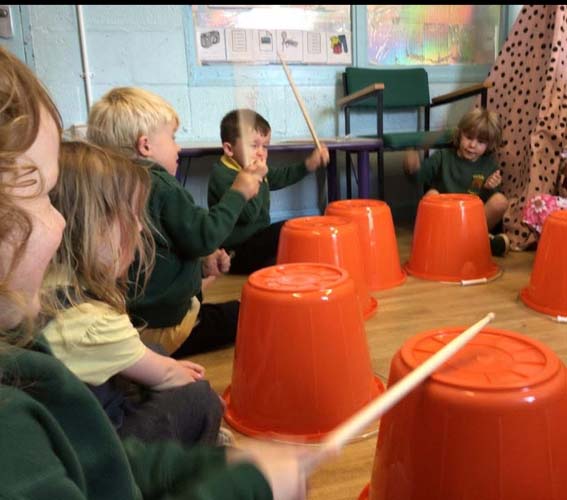 Children playing with drum sticks and orange bucket