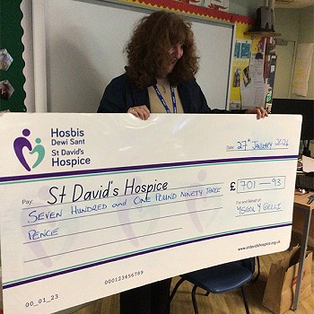 A person holding a big cheque children year 1 and 2 have raised