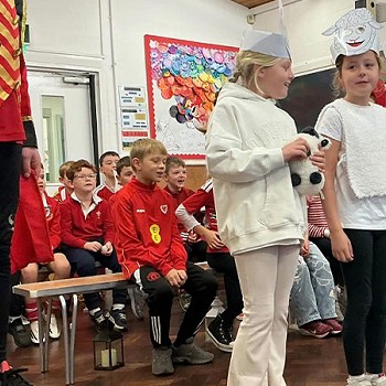 Grŵp o ferched yn gwisgo gwisgoedd defaid fel rhan o olygfa yn y gwasanaeth