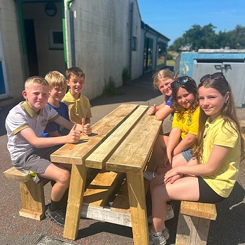 Plant yn eistedd ar y bwrdd ar feinciau mae nhw wedi adeiladu