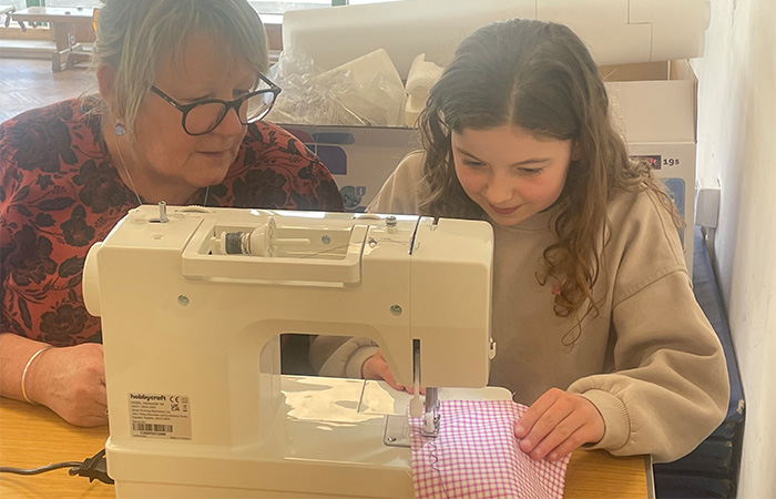 A child developing there sewing machine skills with Anti Gill