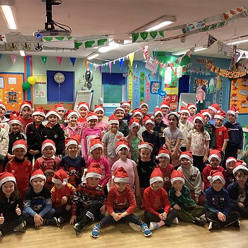 Plant yn gwenu ac yn gwisgo eu hetiau Siôn Corn coch yn yr ystafell ddosbarth