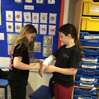 A child putting a bandage on a child's right arm